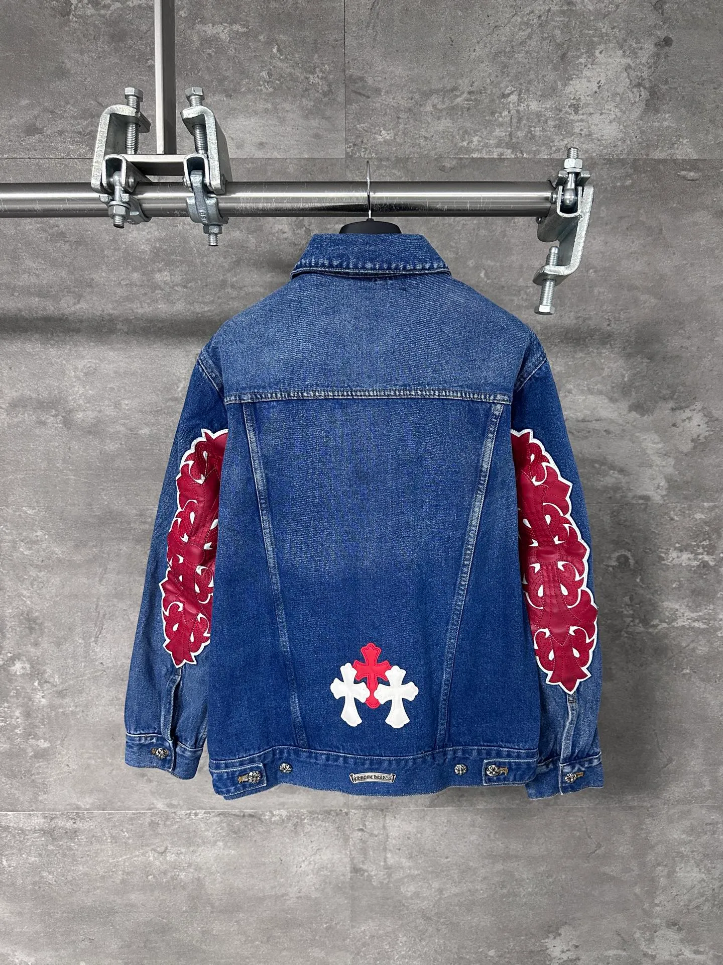 P720 CHrome Hearte cross patchwork leather denim jacket size: S M L Design details: the visual fantasy of Gothic symbols, the multi-dimensional expression of the cross totem: the red and white contrasting cross patches are staggered on the chest and back, making the brand more recognizable; the hollow cross pattern leather splicing on the sleeves combines the mystery of religious symbols with the punk-style deconstructed design. Every detail tells the dark aesthetics of Crowe's heart. Retro distressing with denim texture: Selected denim fabrics are treated with distressing techniques to show natural fading and texture, which not only retains the retro accent of denim items, but also adds a casual sense to the overall look. The ingenuity of hardware and tailoring: The metal buttons and hardware all have Croxin's iconic pattern, which shines exquisitely under the refraction of light; the neat tailoring of the classic denim jacket is suitable for a variety of wearing scenarios, and can create a strong personal style whether it is layered or worn alone. Croxin's denim jacket is not only a piece of clothing, but also a style badge that highlights unique aesthetics and rebellious attitude. For those who pursue individuality, they can leave their own hardcore mark in the fashion field.